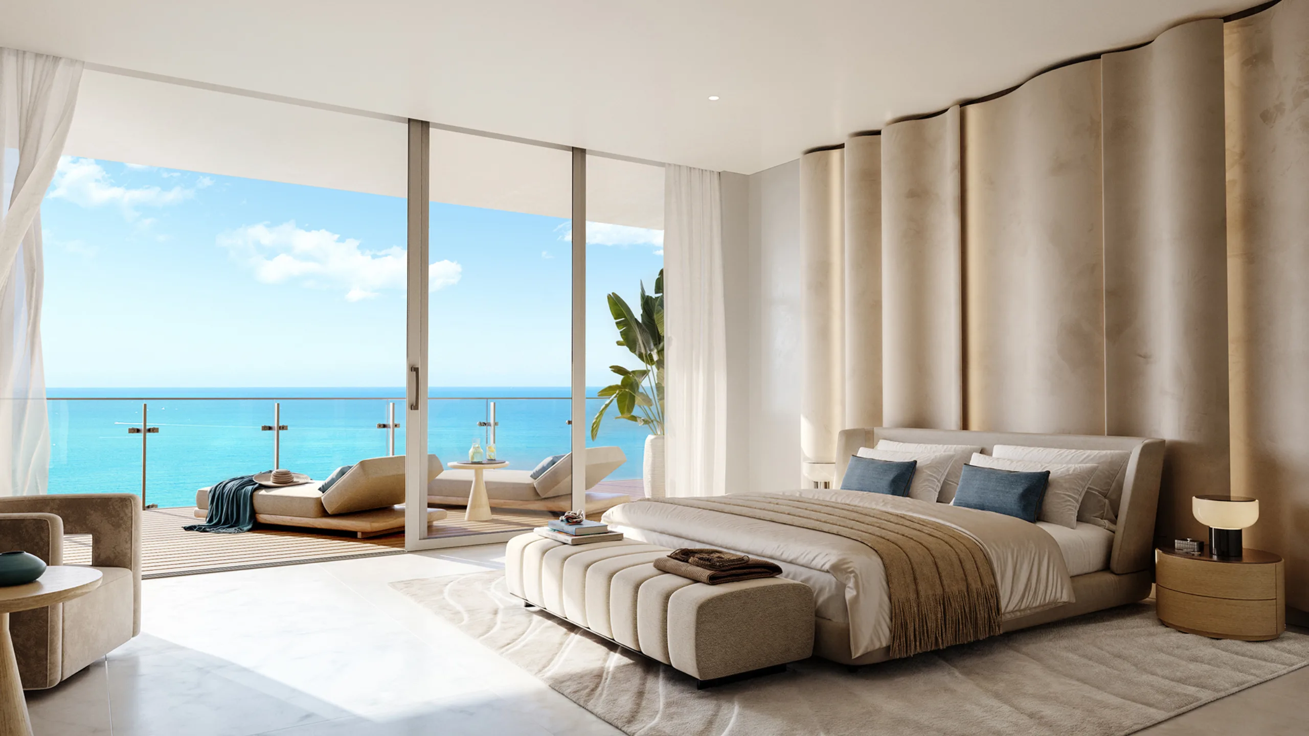 Spacious bedroom with large glass doors opening to a balcony overlooking the ocean