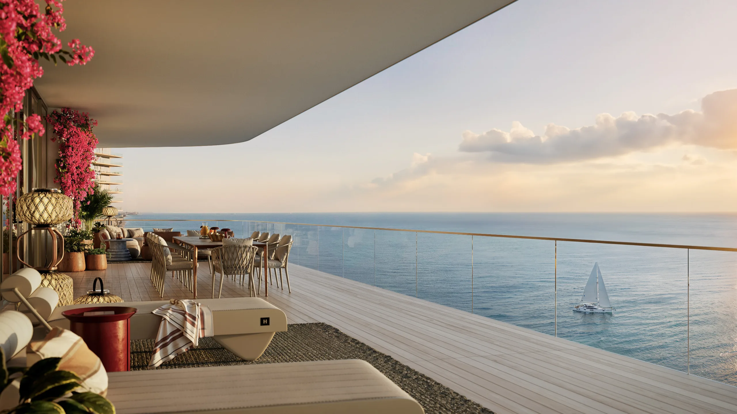 Luxury balcony overlooking the ocean with outdoor dining and pink flowering plants